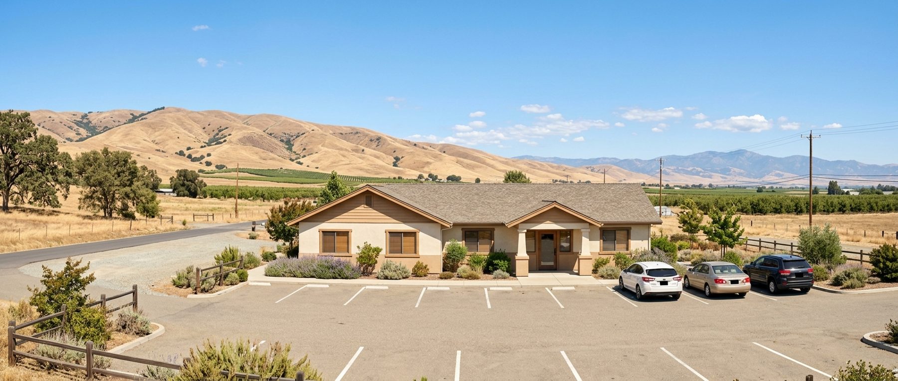 A small single-story rural clinic building set against open foothills and farmland.